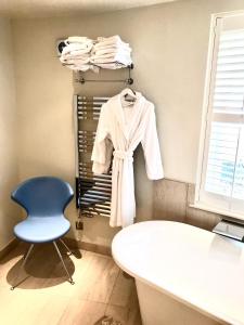 Zimmer mit einem Stuhl und einem weißen Bademantel auf einem Kleiderständer in der Unterkunft College View in Cheltenham