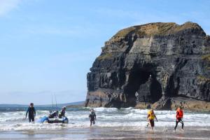 a group of people on the beach with a boat in the water at McMunns of Ballybunion in Ballybunion