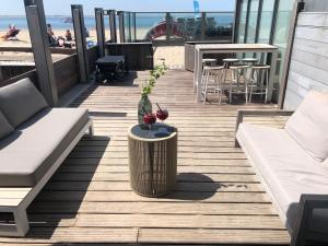 a wooden deck with a table and chairs on the beach at Beachrooms Pier 7 in Vlissingen