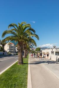 un grupo de personas caminando por una acera con palmeras en Promenade Room Split ****, en Split
