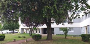 ein weißes Gebäude mit einem Baum davor in der Unterkunft Apparemment vue mer in Aytré