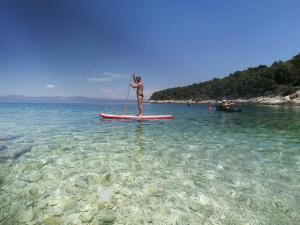 a woman standing on a paddle board in the water at Holiday house Karla in Vela Luka