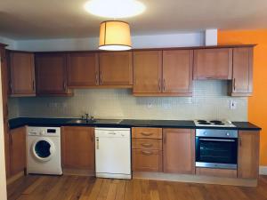 a kitchen with wooden cabinets and a washer and dryer at Apartment 8, Clifden Bay Apartments in Clifden