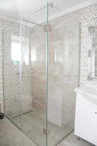 a glass shower in a bathroom with a sink at Kardos Villa in Szigliget
