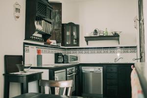 タリファにあるLa Duquesa Guest Houseのキッチン(黒いキャビネット、テーブル、椅子付)