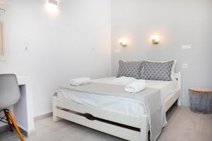 a white bed with two towels on it in a room at Grozos Rooms in Parikia