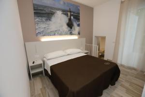 チヴィタノーヴァ・マルケにあるOrchidea Rooms & Suitesのベッドルーム1室(ベッド1台付)が備わります。壁には絵画が飾られています。