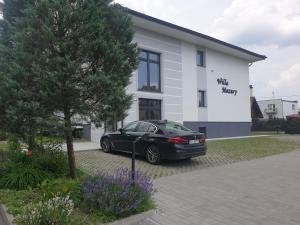 un coche negro estacionado frente a un edificio blanco en Willa Mazury, en Iława