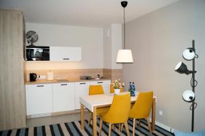 uma cozinha com uma mesa e cadeiras amarelas em Morze-kwatery Apartament BELLA D126 em Międzyzdroje