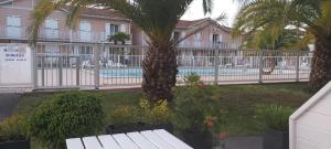 a resort with a pool and palm trees and a fence at RESIDENCE LA CROISIERE- Appt Duplex 6 Personnes in Anglet