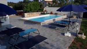 a swimming pool with two tables and two umbrellas at Holiday Home Dioniza in Vodnjan