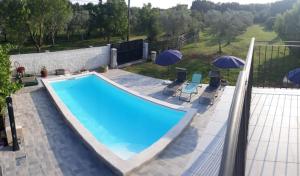 a swimming pool with two umbrellas and two chairs at Holiday Home Dioniza in Vodnjan