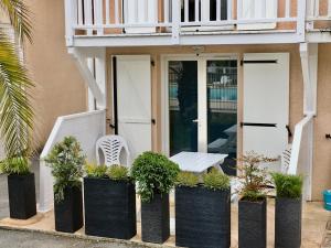 un porche con banco y plantas en contenedores negros en RESIDENCE LA CROISIERE- Appt Duplex 6 Personnes, en Anglet