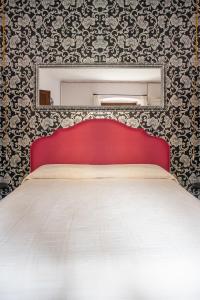 a bed with a red headboard and a mirror at La Babbajola in Iglesias