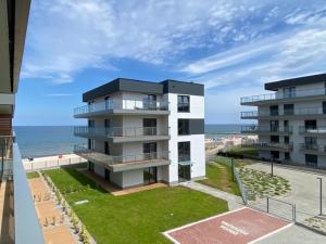 a building next to the beach with the ocean at Apartament SZAFIROWY Gardenia Dziwnów z widokiem na morze in Dziwnów