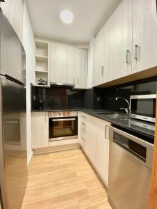 una cocina con armarios blancos y electrodomésticos de acero inoxidable en Ridaura Center Apartment, en Platja d'Aro