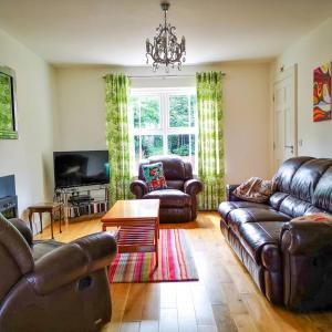 una sala de estar con muebles de cuero y una lámpara de araña. en Holiday Cottages Portsalon, en Portsalon