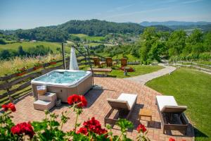 a hot tub on a patio with chairs and flowers at Kuslec Holiday Home in Desinić