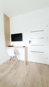 Dieses weiße Zimmer verfügt über einen TV und einen Stuhl. in der Unterkunft Apartament SONIA SAUNA-TARGI-GARAŻ in Kielce