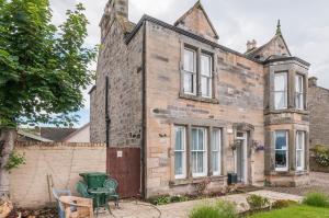 een oud bakstenen huis met een hek en stoelen bij Aynetree Guest House in Edinburgh