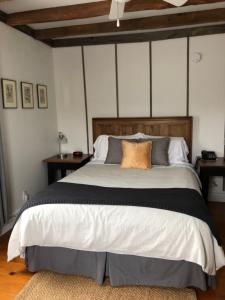 Schlafzimmer mit einem großen Bett mit einem Kopfteil aus Holz in der Unterkunft AUBERGE Knowlton in Lac-Brome
