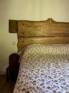een bed in een slaapkamer met een houten hoofdeinde bij Casina del Ponte in Bagno di Romagna