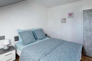 a bedroom with a bed with blue sheets and blue pillows at Comfort Stay Basel Airport 3B46 in Saint-Louis
