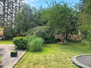 ブロックフスにある7 person holiday home in Blokhusの木のデッキと木々と芝生のある庭園