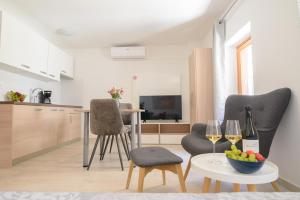 een woonkamer met 2 stoelen en een tafel met wijnglazen bij Old Town Studio in Novigrad Istria