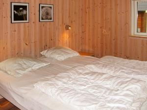 a large white bed in a wood paneled bedroom at Holiday home Idestrup III in Marielyst