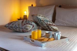 a tray of orange juice and some food on a bed at Madalena's Summer House in Adamantas