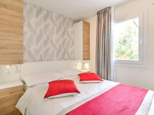 een slaapkamer met een bed met twee rode kussens erop bij Alluring Mobile Home in Banjole with Swimming Pool in Banjole