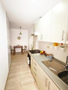 a kitchen with white cabinets and a table in it at Citybeach - parking & wifi in Las Palmas de Gran Canaria