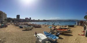 a beach with boats on the sand and a group of people at Citybeach - parking & wifi in Las Palmas de Gran Canaria