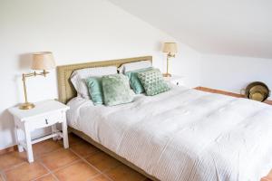 a bedroom with a white bed with green pillows at Monte da Cegonha Preta in Montargil