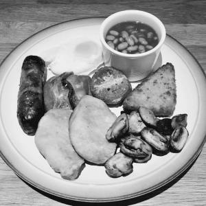 a plate of food with sausage potatoes and beans at Tregorran Guest House Mevagissey in Mevagissey