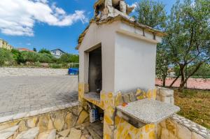 a small building on a stone wall with a bench at Apartments Melita in Trogir