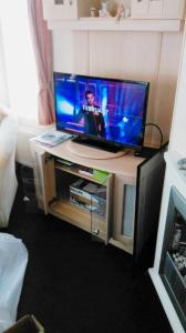 a flat screen tv sitting on top of a table at Caravan by Camber Sands in Camber