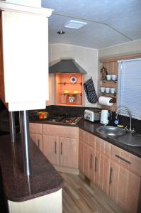 a kitchen with a sink and a stove top oven at Caravan by Camber Sands in Camber