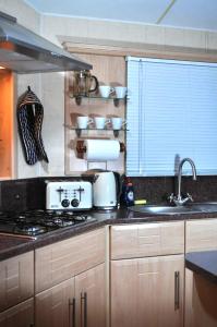 a kitchen with a stove and a sink and a window at Caravan by Camber Sands in Camber