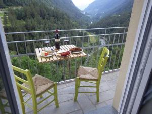 a balcony with a table and chairs and a bottle of wine at AltaValle Holiday Home, monolocale Pink e bilocale Lime in Chiesa in Valmalenco