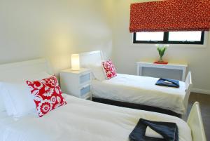 a bedroom with two beds with red and white pillows at The Ridge Gloucester in Gloucester