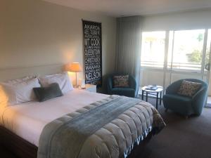 een hotelkamer met een bed en twee stoelen bij Tuscana Motor Lodge in Christchurch