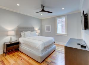 a white bedroom with a bed and a ceiling fan at The Quarters on King in Charleston