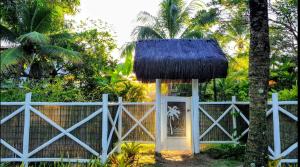a white fence with a gate with a thatch roof at Caiçara Bangalôs Barra Grande Maraú-BA in Barra Grande