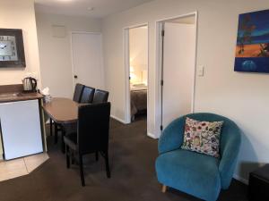 a living room with a blue chair and a table at Tuscana Motor Lodge in Christchurch