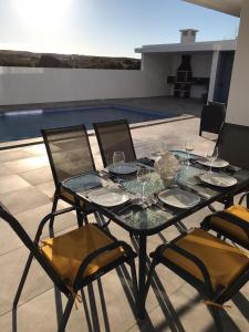 a table with glasses and chairs on a patio at Villa do Barrudo in Vila do Bispo