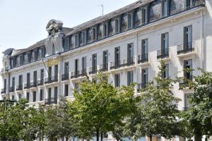 a white building with trees in front of it at Grand Hôtel de Tours in Tours