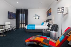 a hotel room with a bed and a table and chairs at Junction Motel in Maryborough