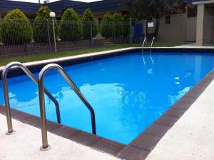 een groot blauw zwembad met metalen leuningen bij Junction Motel in Maryborough